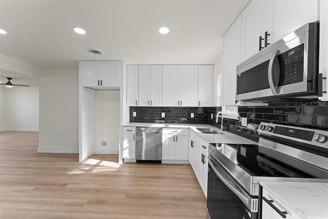 kitchen featuring stainless steel appliances, white cabinets, sink, and light stone countertops