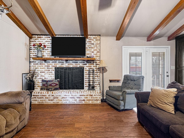 living room with dark wood-type flooring, a brick fireplace, and beamed ceiling