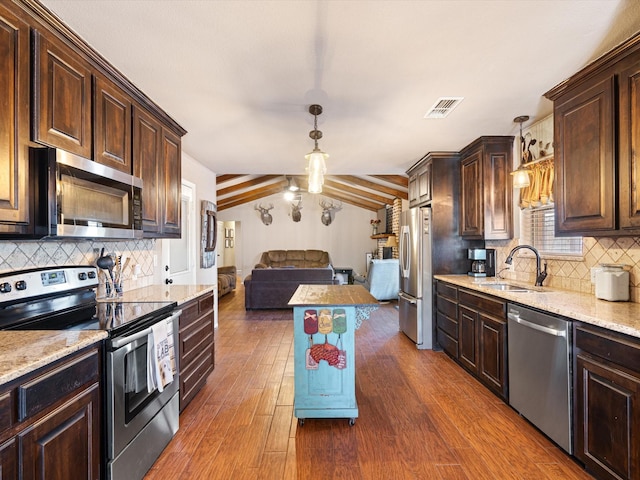 kitchen featuring vaulted ceiling, appliances with stainless steel finishes, pendant lighting, dark hardwood / wood-style floors, and sink