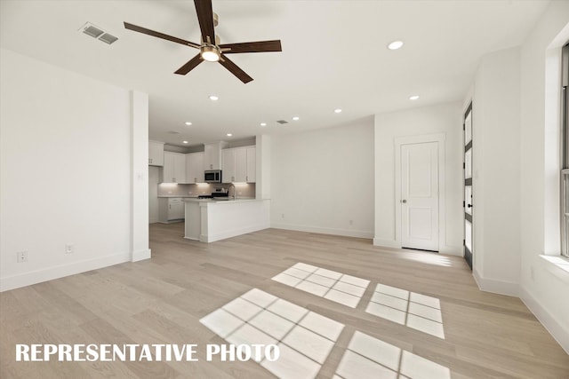 unfurnished living room featuring ceiling fan, light wood-type flooring, and sink