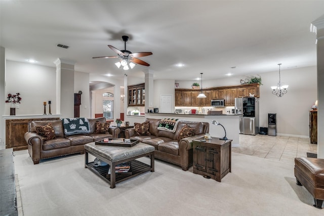 living room featuring light carpet, ceiling fan with notable chandelier, and decorative columns