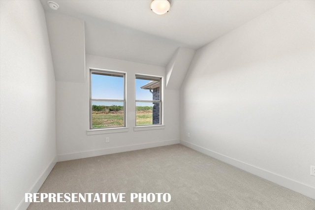 carpeted empty room with lofted ceiling