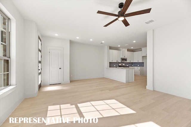 unfurnished living room with ceiling fan, light wood-type flooring, and sink