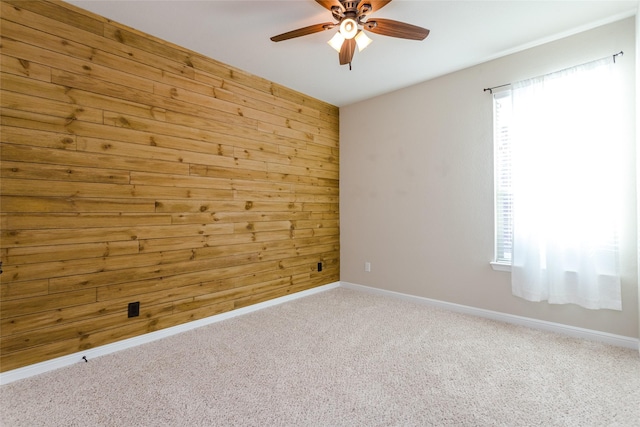 unfurnished room with ceiling fan, wooden walls, and carpet flooring