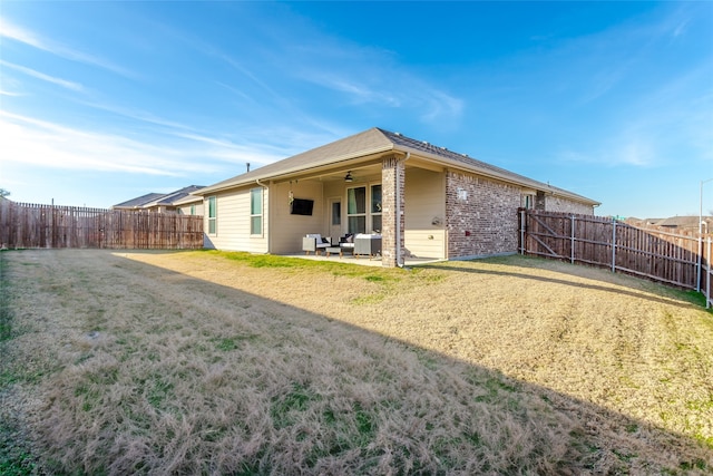 rear view of property with ceiling fan, a yard, and a patio area