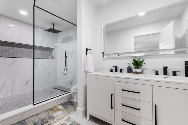 bathroom with toilet, tiled shower, and vanity