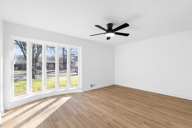 spare room featuring light wood-type flooring, ceiling fan, and plenty of natural light