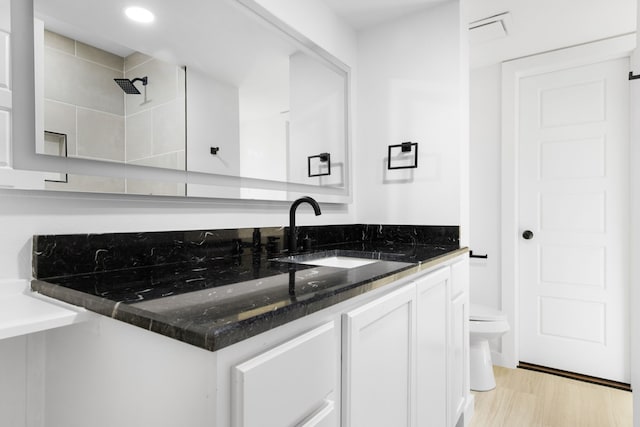 bathroom featuring toilet, vanity, and hardwood / wood-style floors