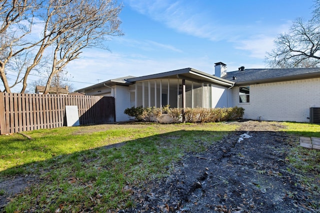 back of house featuring a sunroom and a lawn