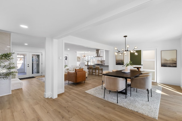 dining space featuring a notable chandelier, light wood-type flooring, french doors, and a wealth of natural light