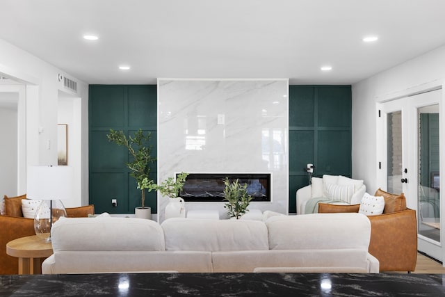 living room with a high end fireplace, french doors, and hardwood / wood-style floors