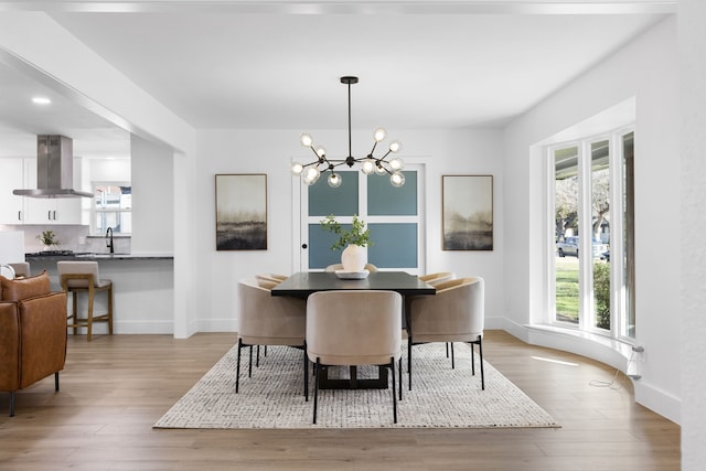 dining space with sink, light hardwood / wood-style floors, a chandelier, and a wealth of natural light