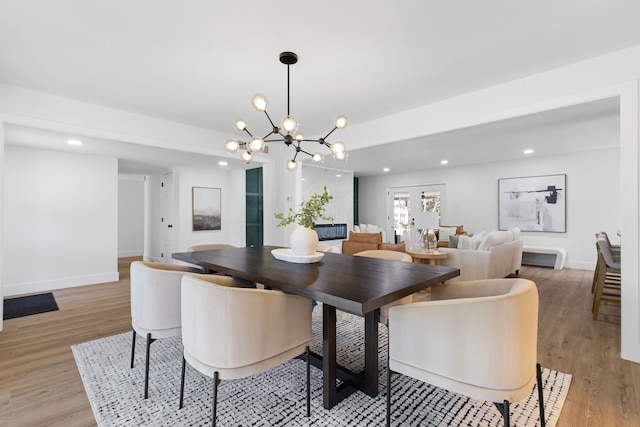 dining area featuring light hardwood / wood-style floors, french doors, and an inviting chandelier