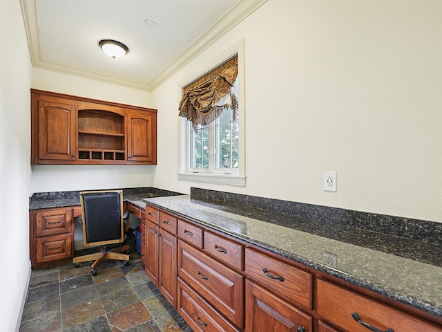 kitchen with built in desk, dark stone countertops, and ornamental molding