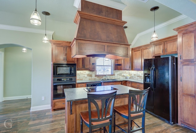 kitchen with a kitchen breakfast bar, black appliances, a kitchen island, decorative light fixtures, and tasteful backsplash