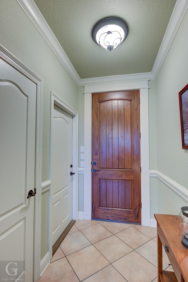 tiled entryway featuring a textured ceiling and ornamental molding