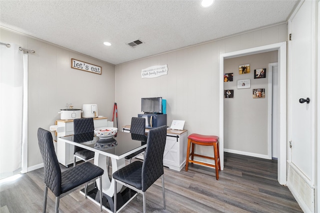 dining space featuring a textured ceiling and dark wood-type flooring