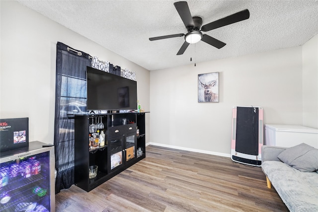 living room featuring a textured ceiling, hardwood / wood-style floors, and ceiling fan