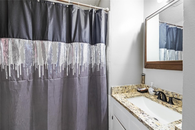 bathroom with vanity, a textured ceiling, and walk in shower