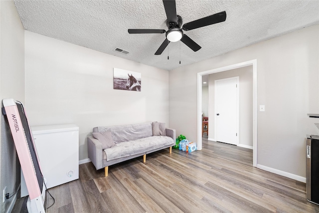 living area featuring a textured ceiling, ceiling fan, and hardwood / wood-style flooring