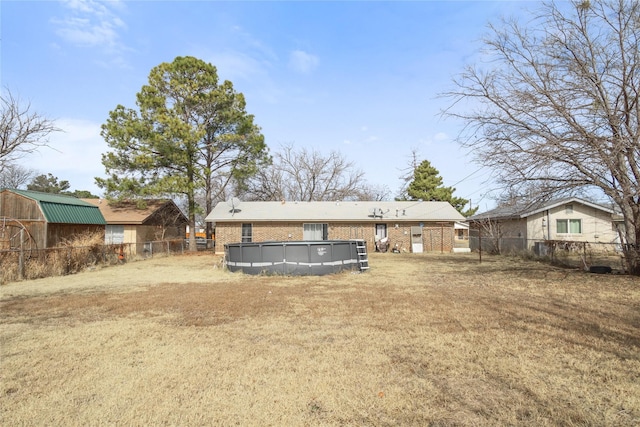 rear view of house featuring a lawn and a fenced in pool