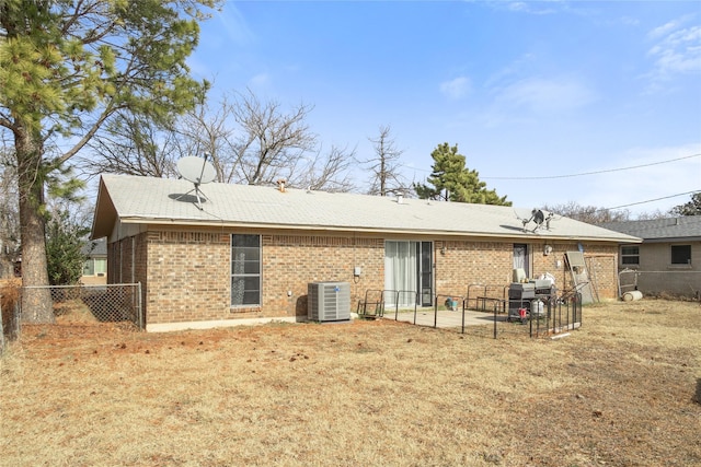 rear view of property with central air condition unit and a yard