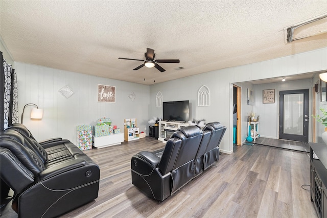 living room featuring wood-type flooring, a textured ceiling, and ceiling fan