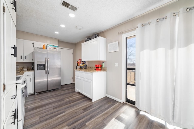 kitchen with a textured ceiling, dark hardwood / wood-style floors, stainless steel refrigerator with ice dispenser, a barn door, and white cabinetry