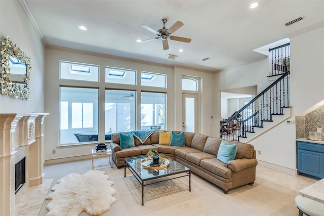 living room with a high end fireplace, ornamental molding, and ceiling fan