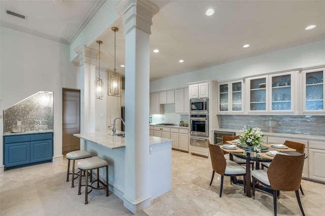 kitchen with white cabinets, decorative backsplash, a kitchen island with sink, and appliances with stainless steel finishes