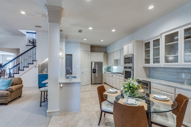 kitchen with stainless steel appliances, light stone countertops, ornamental molding, decorative backsplash, and white cabinets