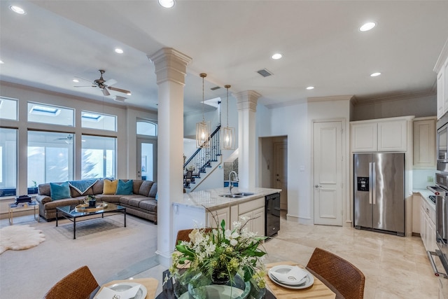 interior space featuring stainless steel appliances, sink, decorative light fixtures, white cabinetry, and ceiling fan with notable chandelier