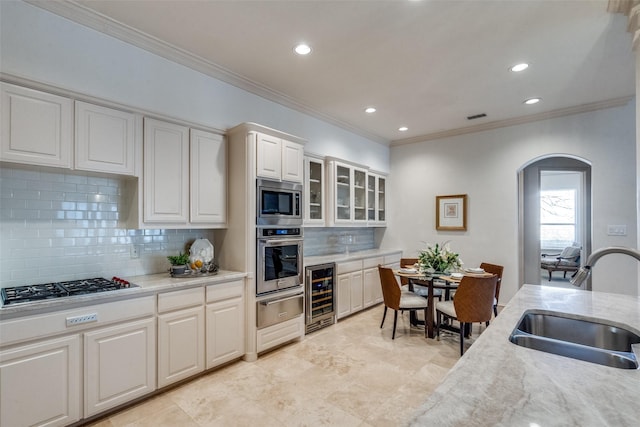 kitchen featuring stainless steel appliances, sink, white cabinetry, backsplash, and wine cooler