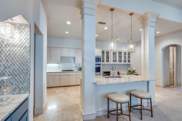 kitchen with sink, white cabinets, decorative light fixtures, a breakfast bar, and appliances with stainless steel finishes