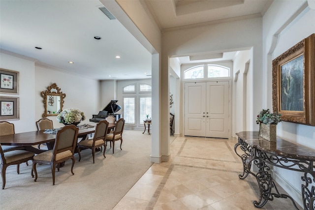 entrance foyer with ornamental molding and light carpet