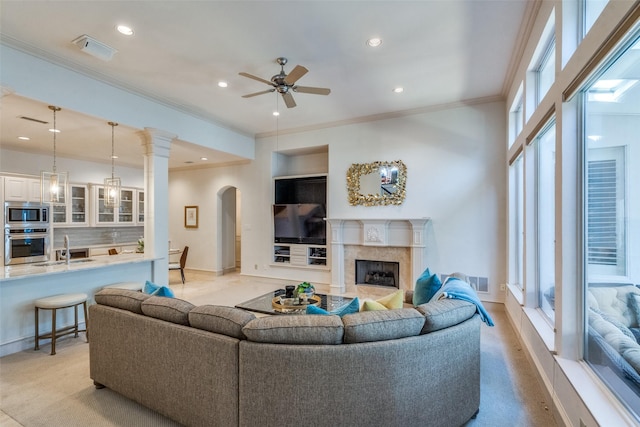 living room with ceiling fan, ornamental molding, a high end fireplace, and sink