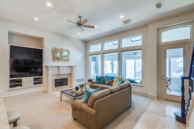 living room featuring ceiling fan, a premium fireplace, ornamental molding, and built in shelves