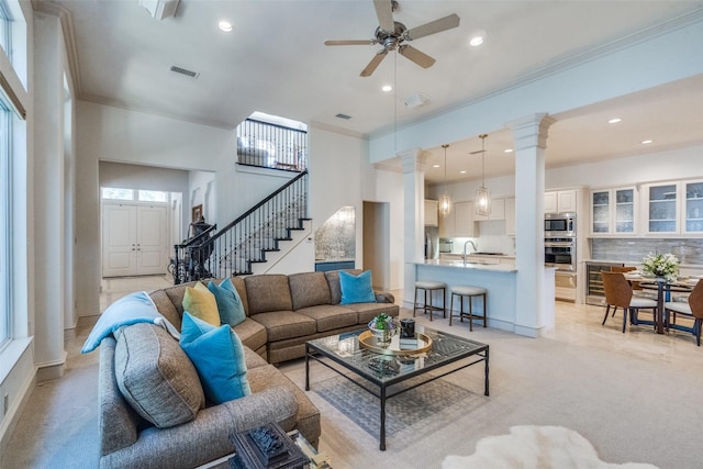 living room featuring beverage cooler, ceiling fan, crown molding, and sink