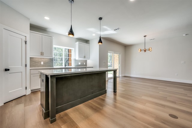 kitchen featuring white cabinetry, an inviting chandelier, pendant lighting, and tasteful backsplash