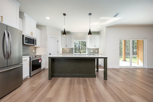 kitchen featuring white cabinets, stainless steel appliances, a kitchen island, and pendant lighting