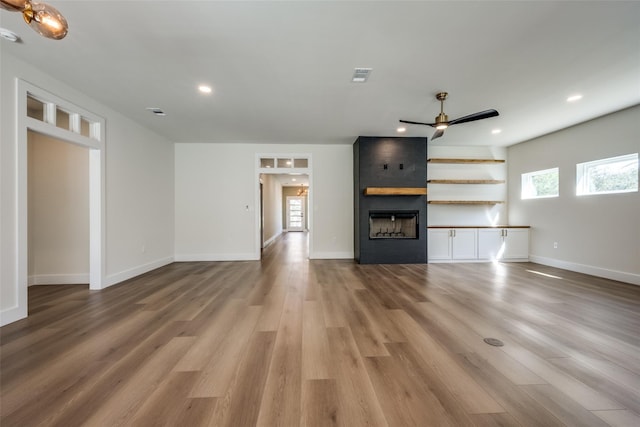 unfurnished living room with a fireplace, ceiling fan, and light hardwood / wood-style flooring