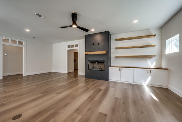 unfurnished living room featuring a fireplace, ceiling fan, and light hardwood / wood-style floors