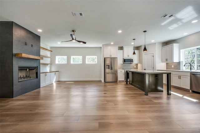 kitchen with white cabinetry, a kitchen breakfast bar, hanging light fixtures, a kitchen island, and appliances with stainless steel finishes