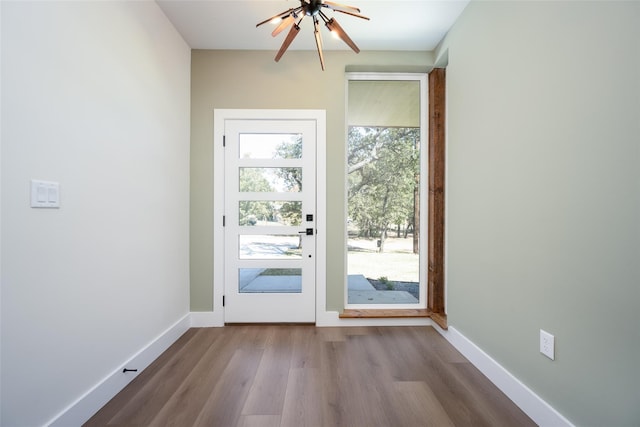 doorway to outside with wood-type flooring, an inviting chandelier, and a healthy amount of sunlight