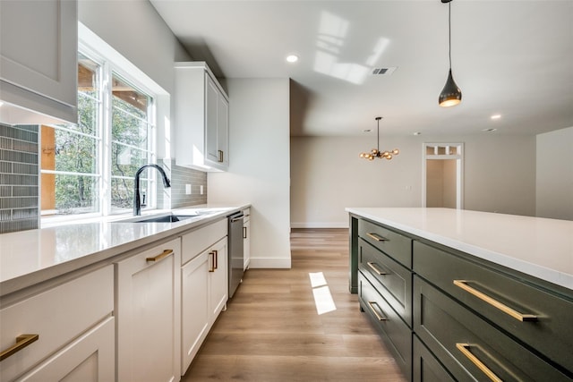 kitchen with dishwasher, decorative light fixtures, tasteful backsplash, white cabinets, and sink