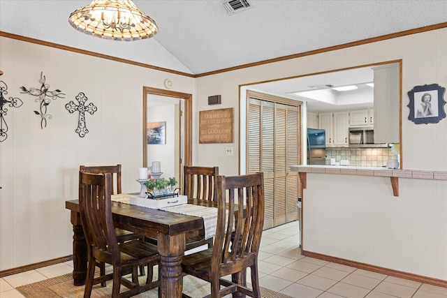 dining area with lofted ceiling, a textured ceiling, light tile patterned floors, and a chandelier