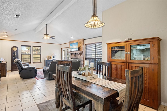 tiled dining space featuring a healthy amount of sunlight, vaulted ceiling with beams, a fireplace, and a textured ceiling