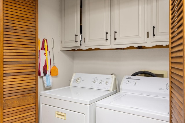 clothes washing area featuring cabinets and washing machine and clothes dryer