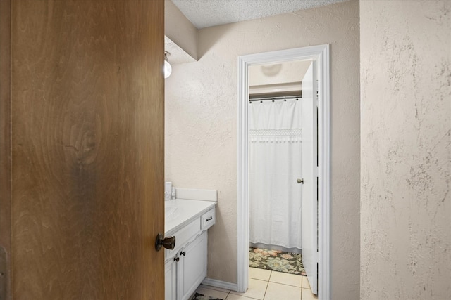 bathroom with tile patterned flooring, a textured ceiling, a shower with shower curtain, and vanity