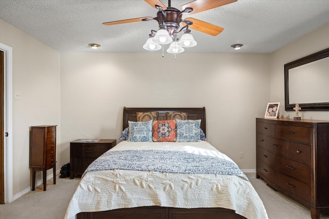 bedroom with a textured ceiling, ceiling fan, and light carpet